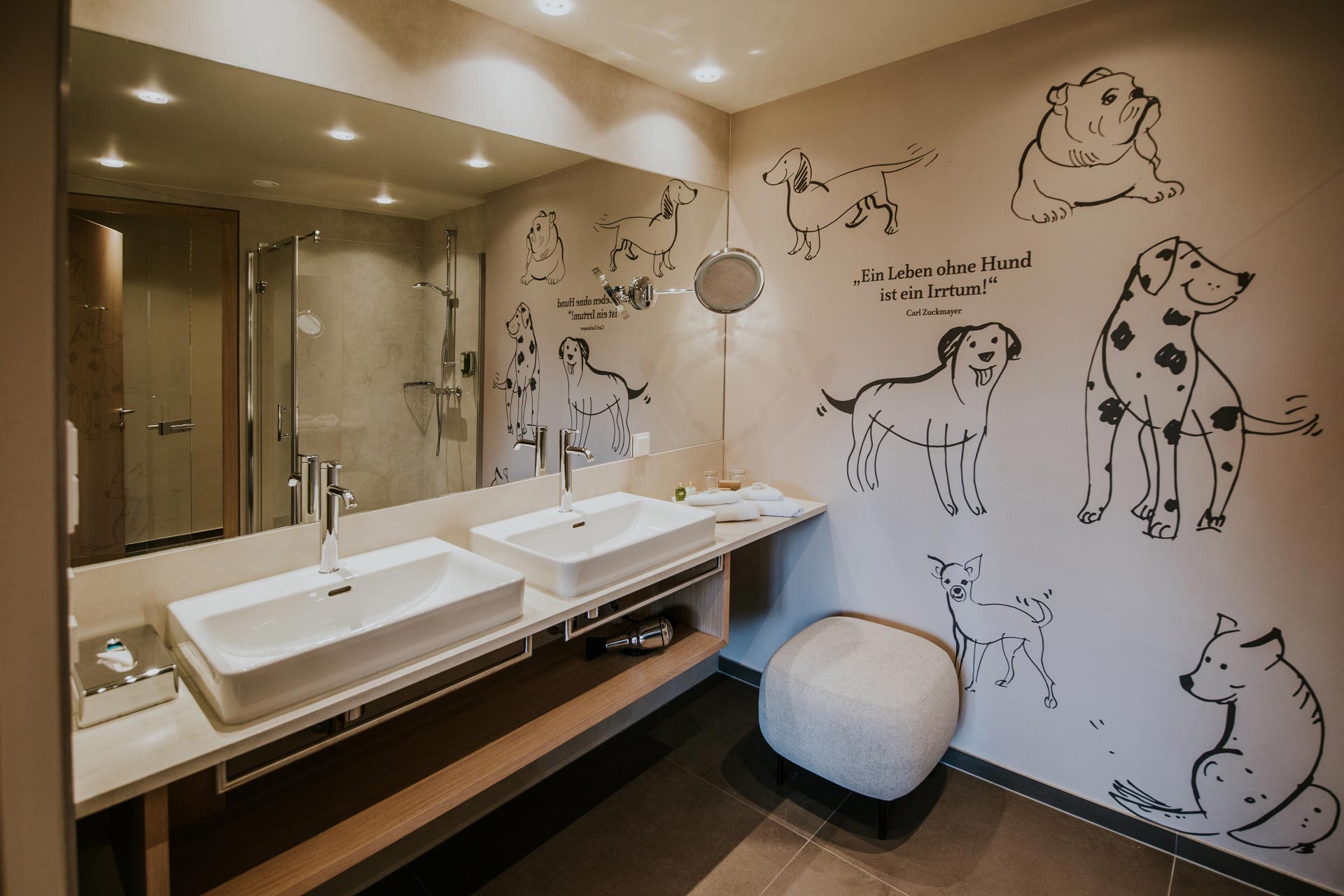 Badezimmer mit Doppelwaschbecken der WOW Suite mit Hundezeichnungen und dem Spruch "Ein Leben ohne Hund ist ein Irrtum" an der Wand